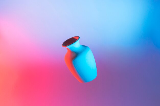 Ceramic vase in air against colorful light backdrop