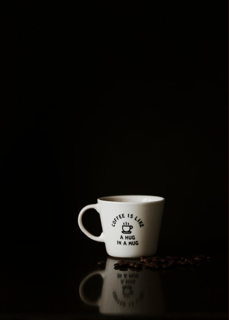 Ceramic white cup with roasted coffee beans on black background