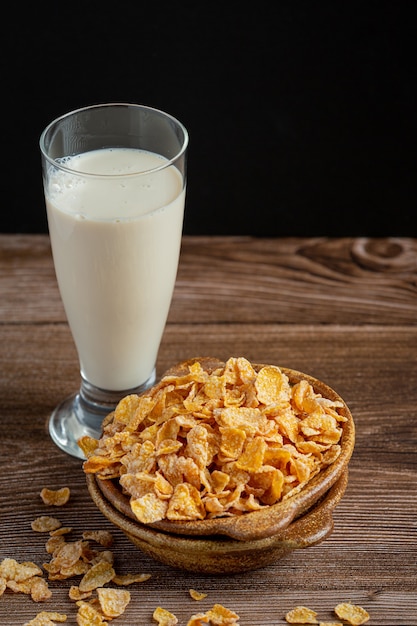 Cereali in ciotola e latte su fondo di legno scuro