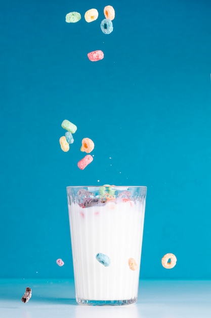 Cereal fruit loops pouring in a glass of milk