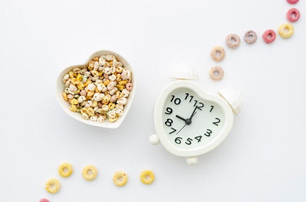 Cereals and clock on white background