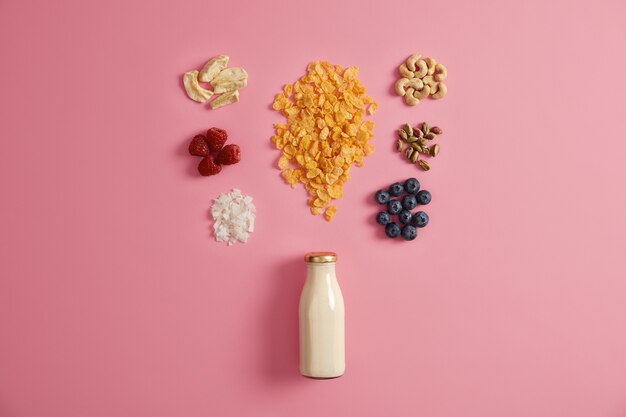 Cereals with dried apples, dates, cashew, pistachio around bottle with milk