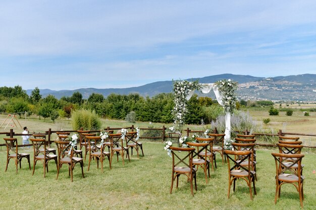 屋外のゲストのための結婚式のアーチ道とキアヴァリの椅子