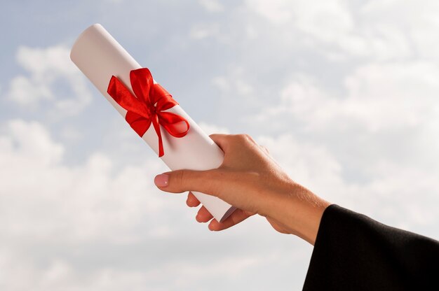 Certificate with ribbon and bow held in hand