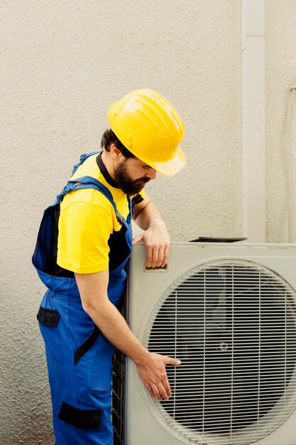 Certified technician getting new outdoor air conditioner ready after replacing old busted unit. Trained engineer contracted to install new condenser and make sure it operates at maximum power