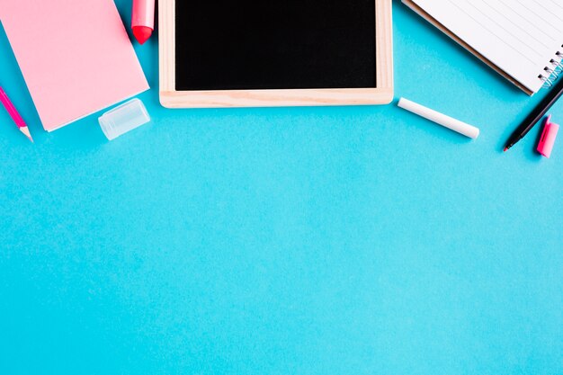 Chalk board and notepads on colored background