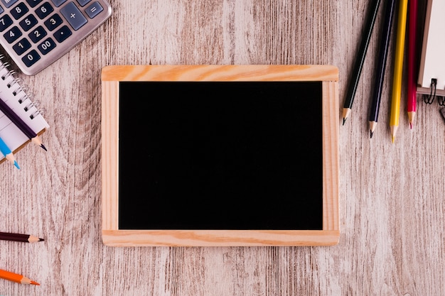 Chalk board and stationery on wooden surface