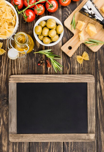 Free photo chalkboard beside fusilli with olives and vegetables