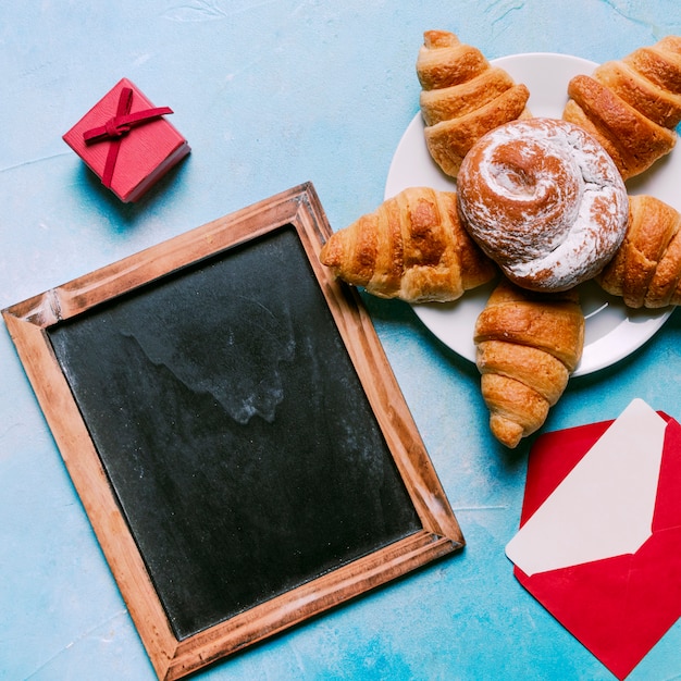 Chalkboard with croissants and bun on plate