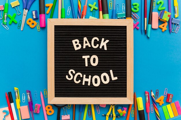 Chalkboard with group of school supplies on a blue background.