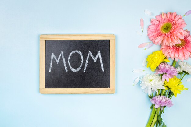 Chalkboard with mom title near bunch of fresh bright flowers