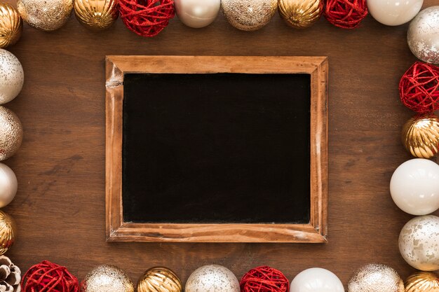 Chalkboard with shiny baubles on table 