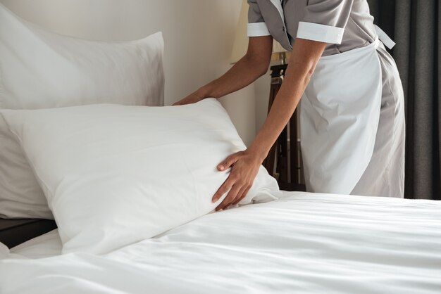 chambermaid making bed in hotel room