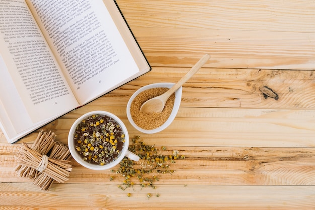 Free photo chamomile tea and brown sugar near book