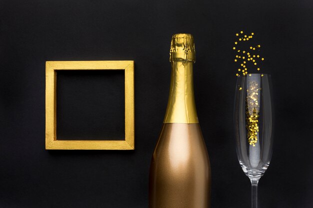 Free photo champagne bottle with glass and frame