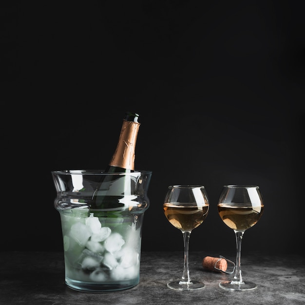 Foto gratuita bottiglia di champagne con bicchieri sul tavolo