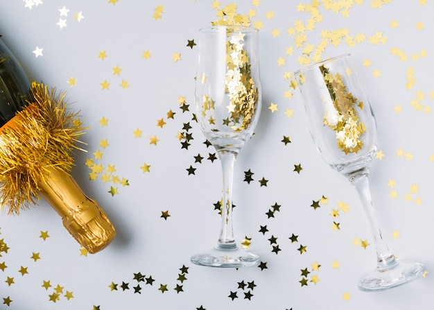 Free photo champagne bottle with spangles in glasses