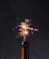 Foto gratuita bottiglia di champagne con stelle filanti su sfondo nero