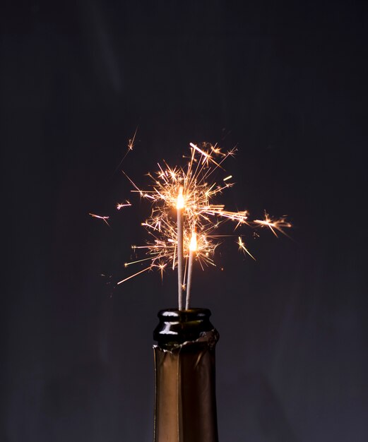 Champagne bottle with sparklers on black background