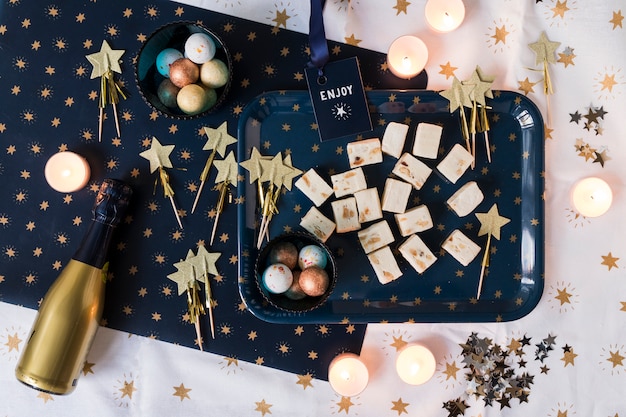 Champagne bottle with sweets on table 