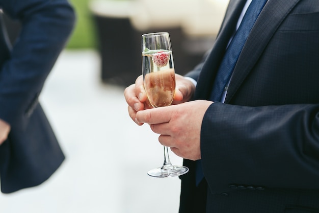 Champagne flute held by a man in black jacket