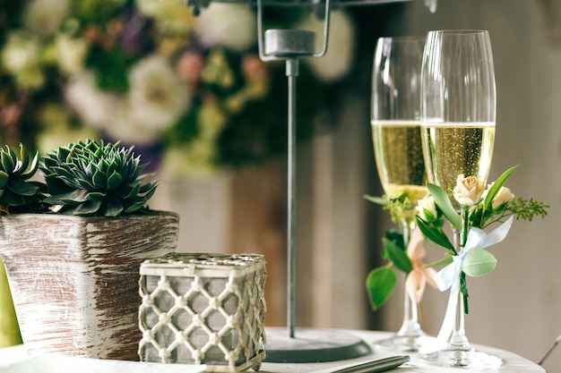 Champagne flutes decorated with tiny roses stand on table