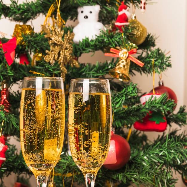 Free photo champagne glasses in front of christmas tree