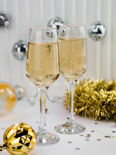 Free photo champagne glasses with golden globe and tinsel