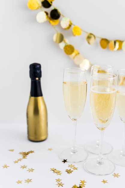 Foto gratuita bicchieri di champagne con piccoli lustrini sul tavolo