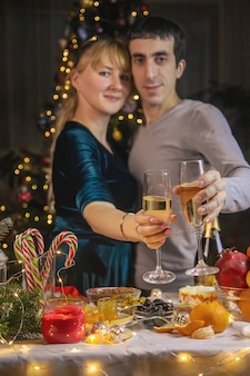 クリスマスツリーを背景にシャンパンを手に。人。セレクティブフォーカス。ホリデー。 Premium写真