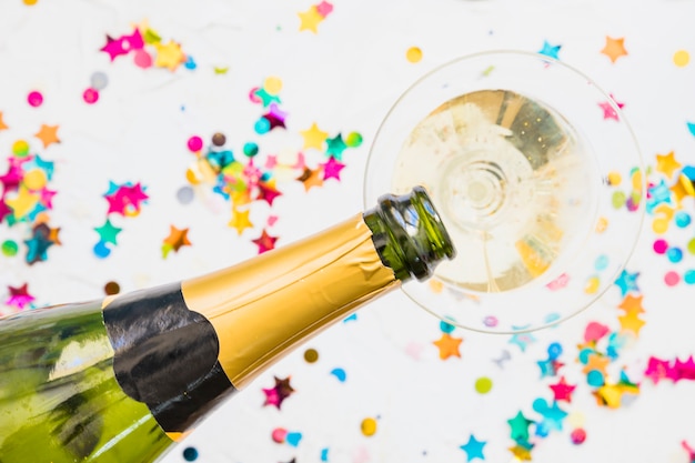 Champagne pouring in glass from bottle on table 