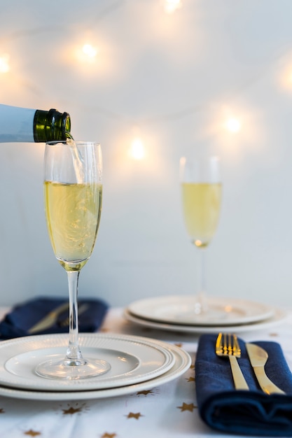 Foto gratuita champagne che versa in vetro sul piatto bianco