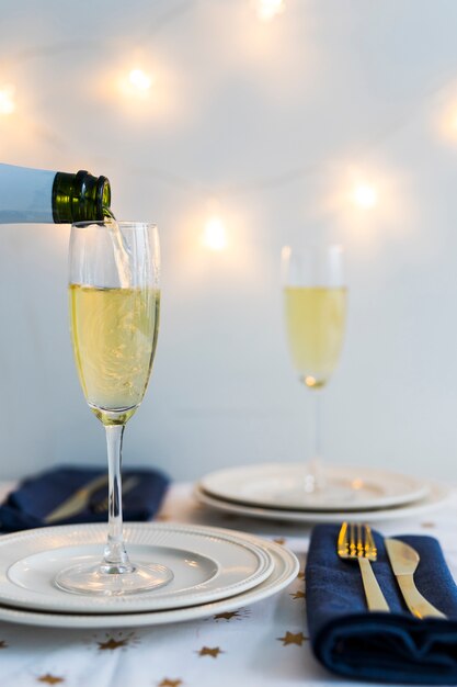 Champagne pouring in glass on white plate