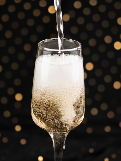 Foto gratuita champagne che versa in vetro con schiuma