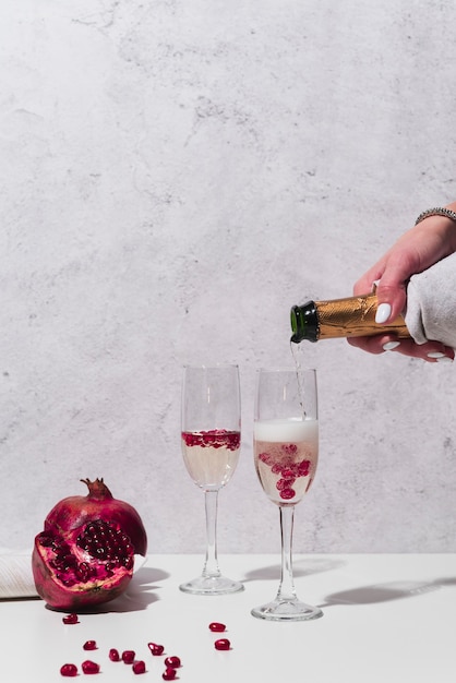 Champagne pouring into glass with pomegranate