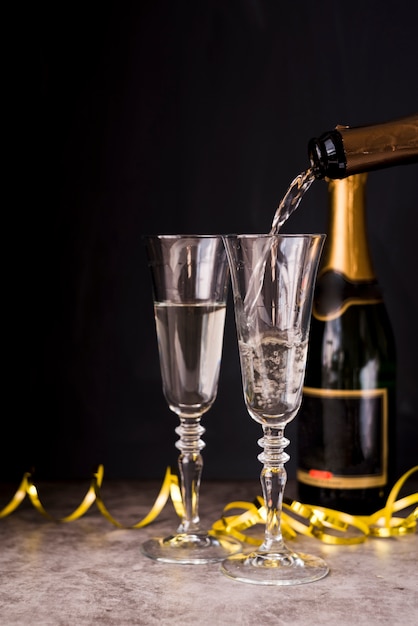 Шампанское льется в бокал с серпантином на вечеринке