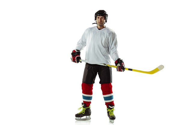 Foto gratuita campione. giovane giocatore di hockey maschio con il bastone sul campo da ghiaccio e muro bianco. sportivo che indossa attrezzature e pratica del casco. concetto di sport, stile di vita sano, movimento, movimento, azione.