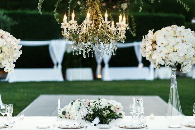 Chandelier with flowers and greenery hangs over dinner table