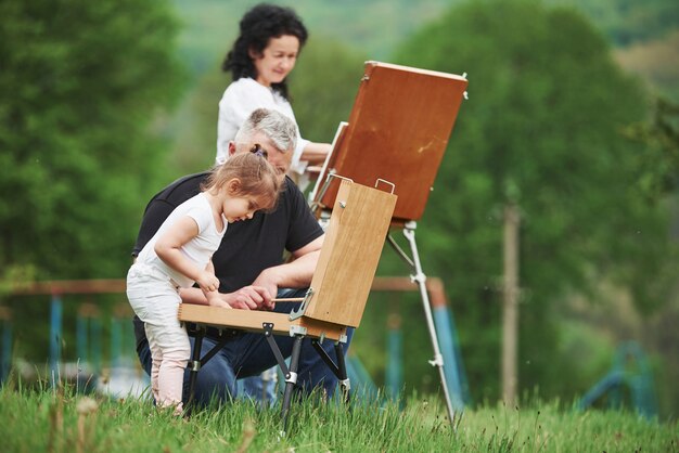 Меняем цвета. Бабушка и дедушка веселятся на природе с внучкой. Концепция живописи