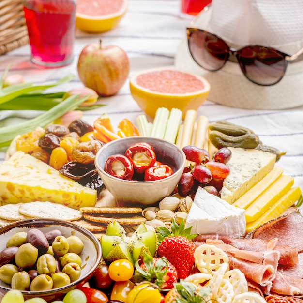 Foto gratuita tagliere di salumi con affettati, frutta fresca e formaggi, picnic estivo