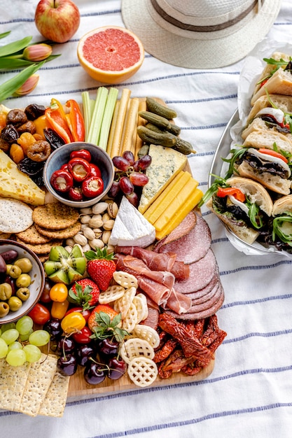 Колбасная доска с мясным ассорти, свежими фруктами и сыром, летний пикник