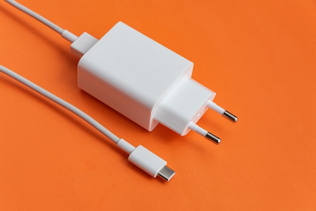 Бесплатное фото Зарядное устройство и usb-кабель типа c на оранжевом фоне