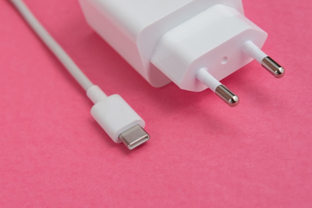 Зарядное устройство и USB-кабель типа C на розовом фоне