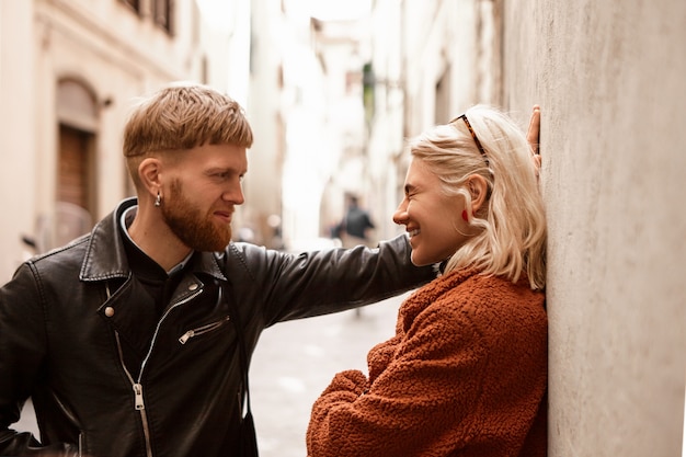 Charismatic confident young macho man with thick ginger beard and stylish haircut driving cute laughing blonde stranger woman to wall, asking her out on date. Love, togetherness and romance concept
