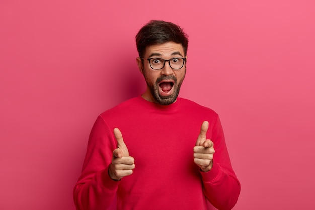 Charismatic excited unshaven man points directly