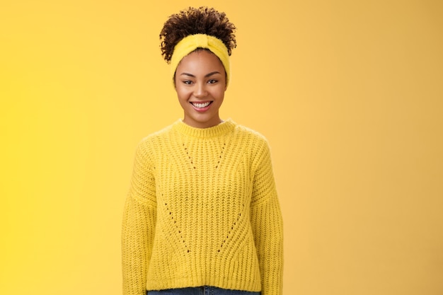 Foto gratuita carismatico amichevole sorridente ragazza nera fascia ricci acconciatura afro ghignando con gioia eccitato partecipare all'evento universitario aiutando in piedi in uscita energizzato sfondo giallo.