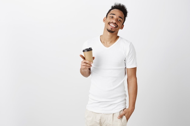 Харизматичный красивый афро-американский мужчина улыбается и пьет кофе