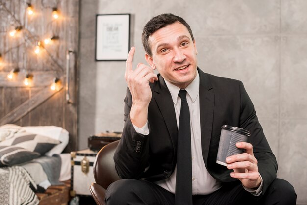 Charismatic male pondering while holding cup of coffee in his hand