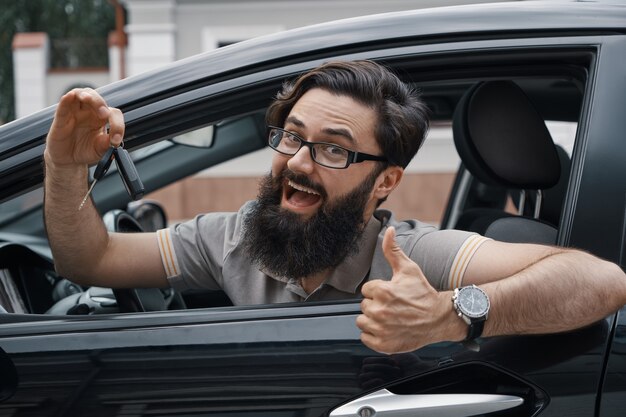 Charismatic man holding car keys showing thumbs up