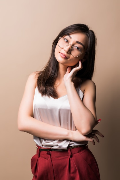 charming asian woman standing isolated over beige wall